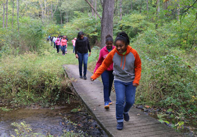 Students from Serviam Academy walk on a footbridge across White Clay Creek.