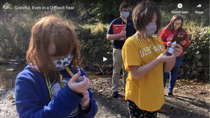 Video still showing masked students performing stream water chemistry tests.