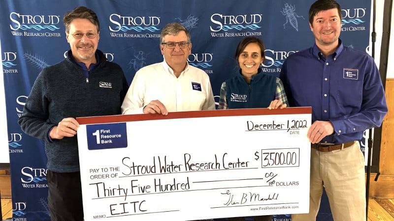 Staff from First Resource Bank and the Stroud Center hold an oversized check representing a donation.