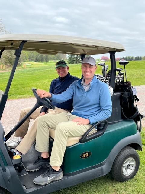 Two men in a golf cart at the 2022 Fore Fresh Water golf outing.