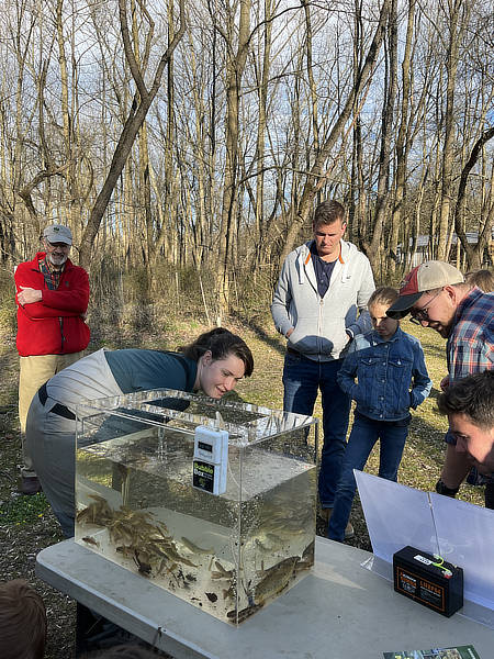 A scientist shows adults and children live fish from White Clay Creek.