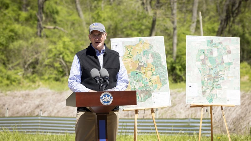 Department of Agriculture Secretary Russell Redding speaks at a podium in a farm field.