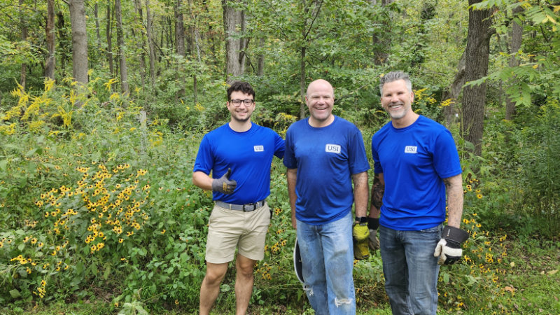 Three USI volunteers remove invasive plants on the Stroud Center campus.