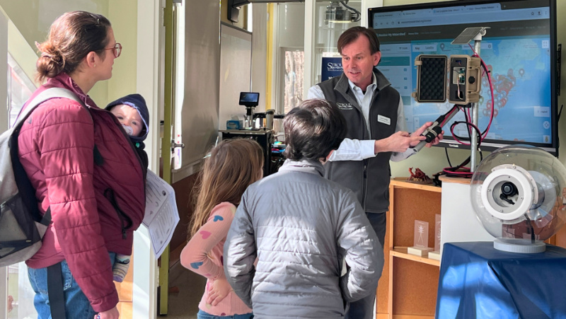 Scott Ensign explaining WikiWatershed technology to a family at World Water Day.
