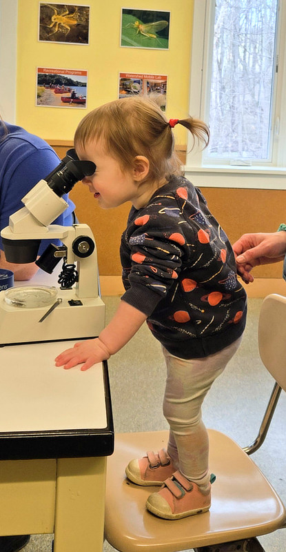 A toddler looks through a microscope at World Water Day 2026.