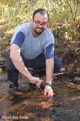 A workshop participant secures an artificial leaf pack in a stream.