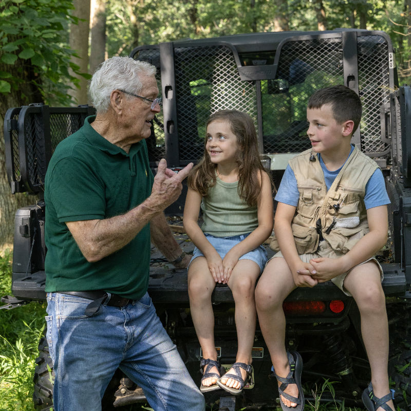 Coach Vermeil talks with kids in a streamside forest.