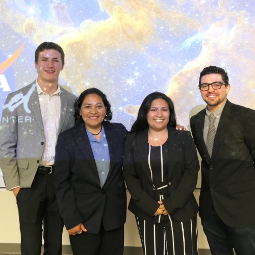 Four NASA DEVELOP interns stand in front of a starry background.