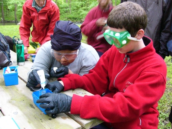 Brandywine Trekkers perform a water chemistry test wearing protective gear.