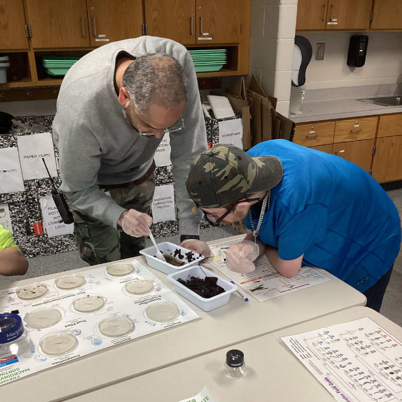 A student and teacher sort through leaf pack contents.