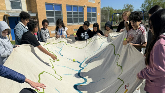 Students using the watershed tapestry to show how water moves through a waterched.