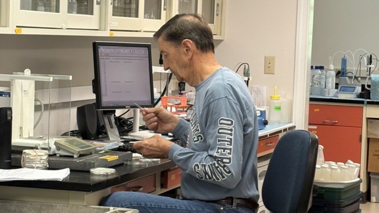 Retired scientists Bern Sweeney working in the lab, summer 2026.