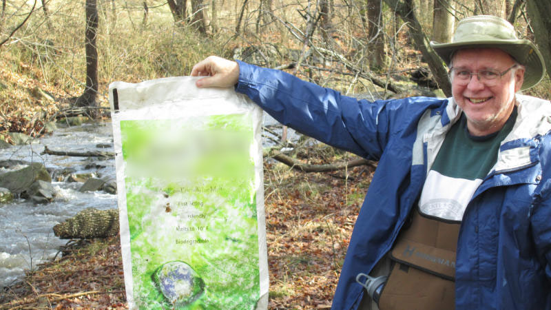 Man holding a plastic bag that he removed from a nearby stream.