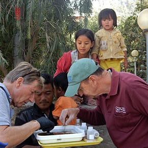 Peter Kjellerup and Bern Sweeney sorting aquatic macroinvertebrates as Bhutanese children watch.