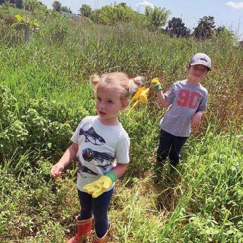 Two children helping wearing work glove and boots help maintain a streamside forest buffer.