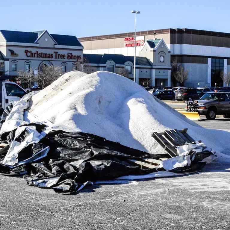An improperly stored road salt pile in a shopping center parking lot.