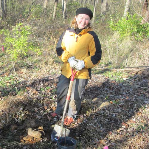 Carol Armstrong planting a tree in a streamside forest.