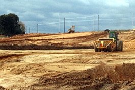 Construction equipment on a large area of bare soil.