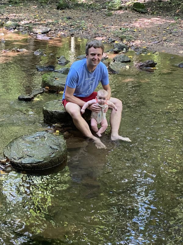 Daniel Myers tips his baby's toes in a stream.