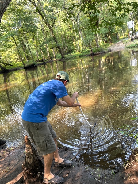 Scott Ensign collecting a sediment sample from a river.