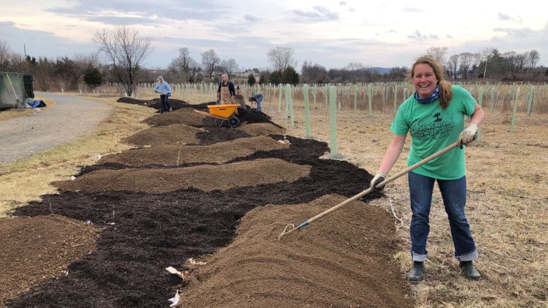 Volunteers rake soil into place for a new pollinator garden.