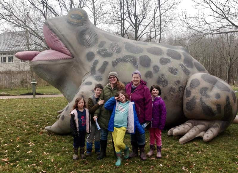 Two women and four children pose in front of a giant inflatable frog.