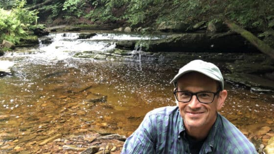 Lamonte Garber in front of a Sullivan County, Pa. stream with a small waterfall.