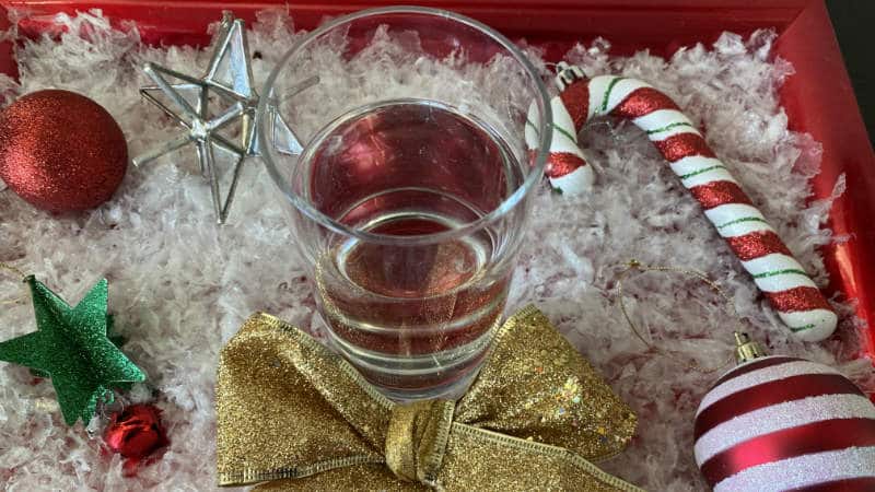 A red box with holiday ornaments, and a glass of water in the middle.