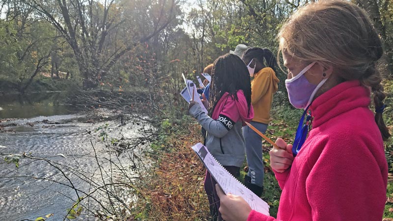 A group of masked girls surveying a stream habitat.