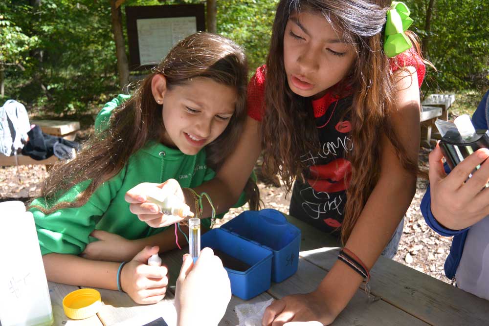 Girls performing a water chemistry test as part of a stream study