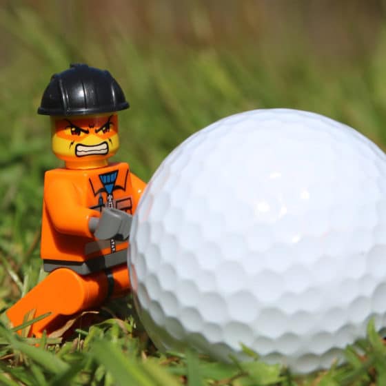 Photo of an angry Lego figurine pushing a golf ball.