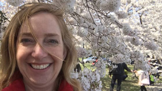 Jen Merrill in front of a blooming cherry tree.