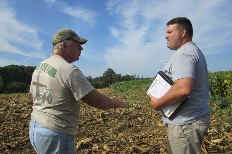 Farmers Jeremy Weaver and Jeff Frey talking at a no-till farm field.