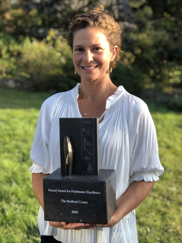 Photo of Jill Tidman, executive director of The Redford Center, holding the 2020 Stroud Award for Freshwater Excellence sculpture.