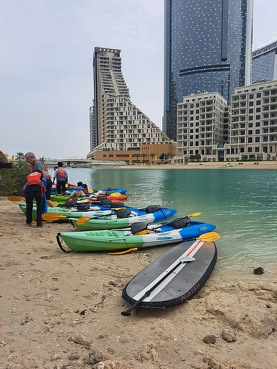 Kayaks lined up on the sand near a waterway in Dubai.