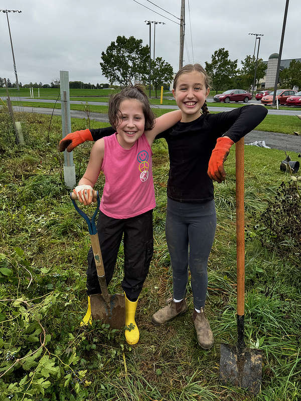 Two girls take a break from rescuing trees from invasive vines.