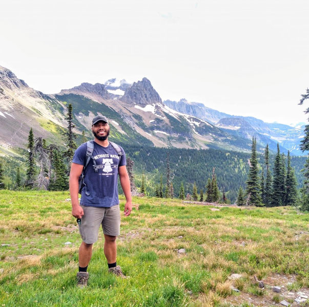 Lee Clark backpacking in Montana with mountain ranges in the background.