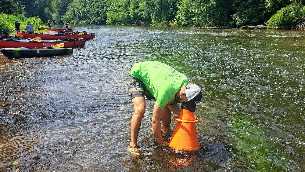 A teacher uses an orange bathyscope to view underwater life in the Conestoga.