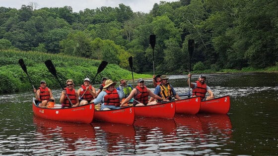 Pairs of teachers in five red canoes on the Conestoga River.