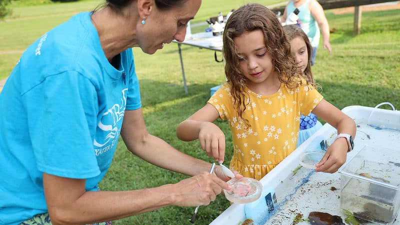 Tara Muenz helps a child at the aquatic macroinvertebrate touch tank.
