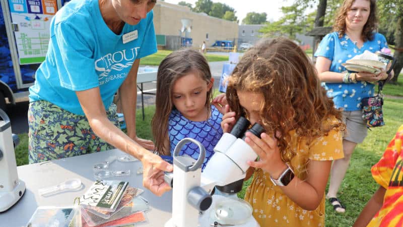 Tara Muenz helps a child focus a microscope to see aquatic macroinvertebrates.