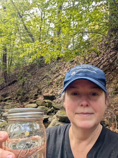 A Master Watershed Steward holds her salt snapshot sample jar.