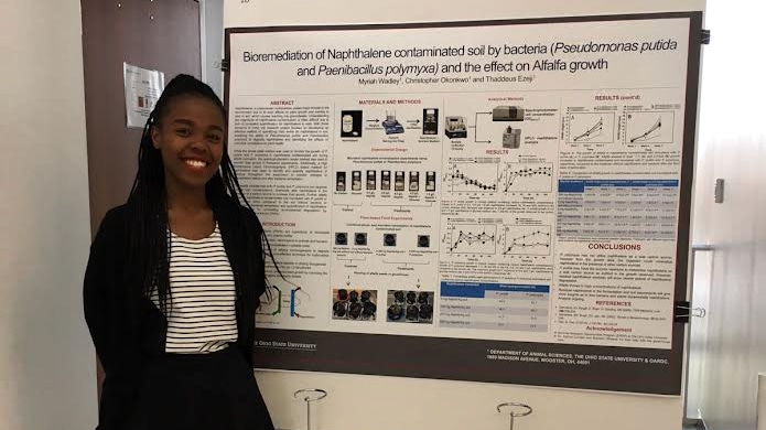Myriah Wadley with her research poster about bioremediation of napthalene contaminated soil.