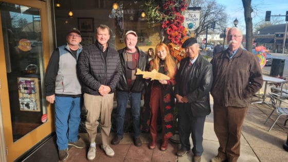 Mandy Nix holding a wooden fish plaque while surrounded by Trout Unlimited members.