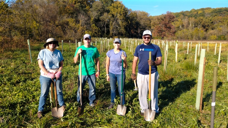 A group of volunteers with shovels at a tree planting event.