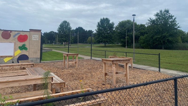 A high school outdoor classroom with benches, tables, and mural art.