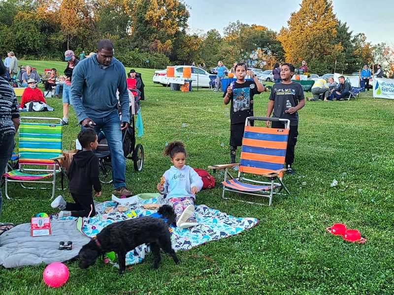 Family with dog, children blowing bubbles at an outdoor festival.