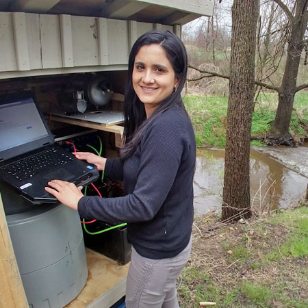 Diana Oviedo-Vargas downloading data from a sensor located in White Clay Creek to a field laptop.