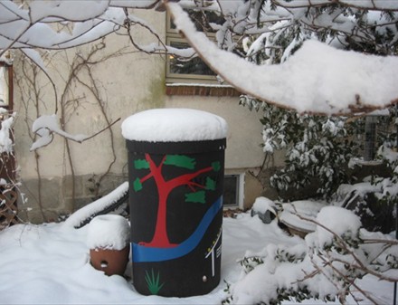 A painted rain barrel in the snow.