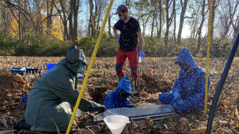 Four scientists collect simulated rainfall from soil in a cornfield in White Clay Creek watershed.